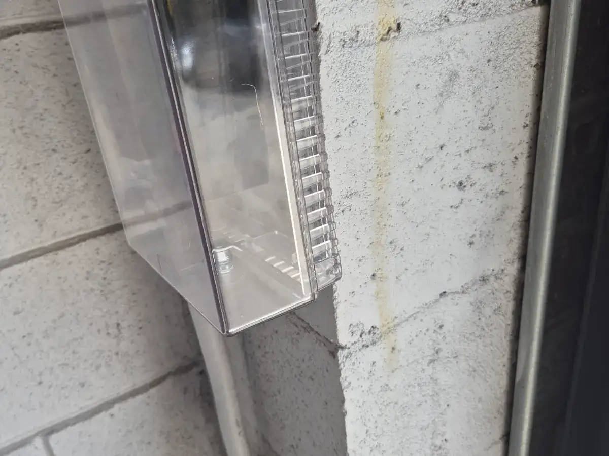 Clear protective cover of a gate control station mounted on a painted block wall