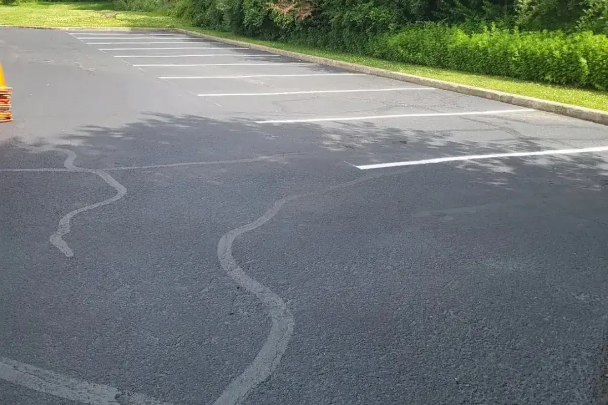 Freshly sealcoated asphalt parking lot with hot tar crack filling and new white stall lines