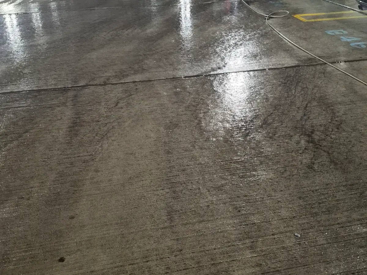 Wet concrete parking deck after washing, light reflecting off the cleaned surface